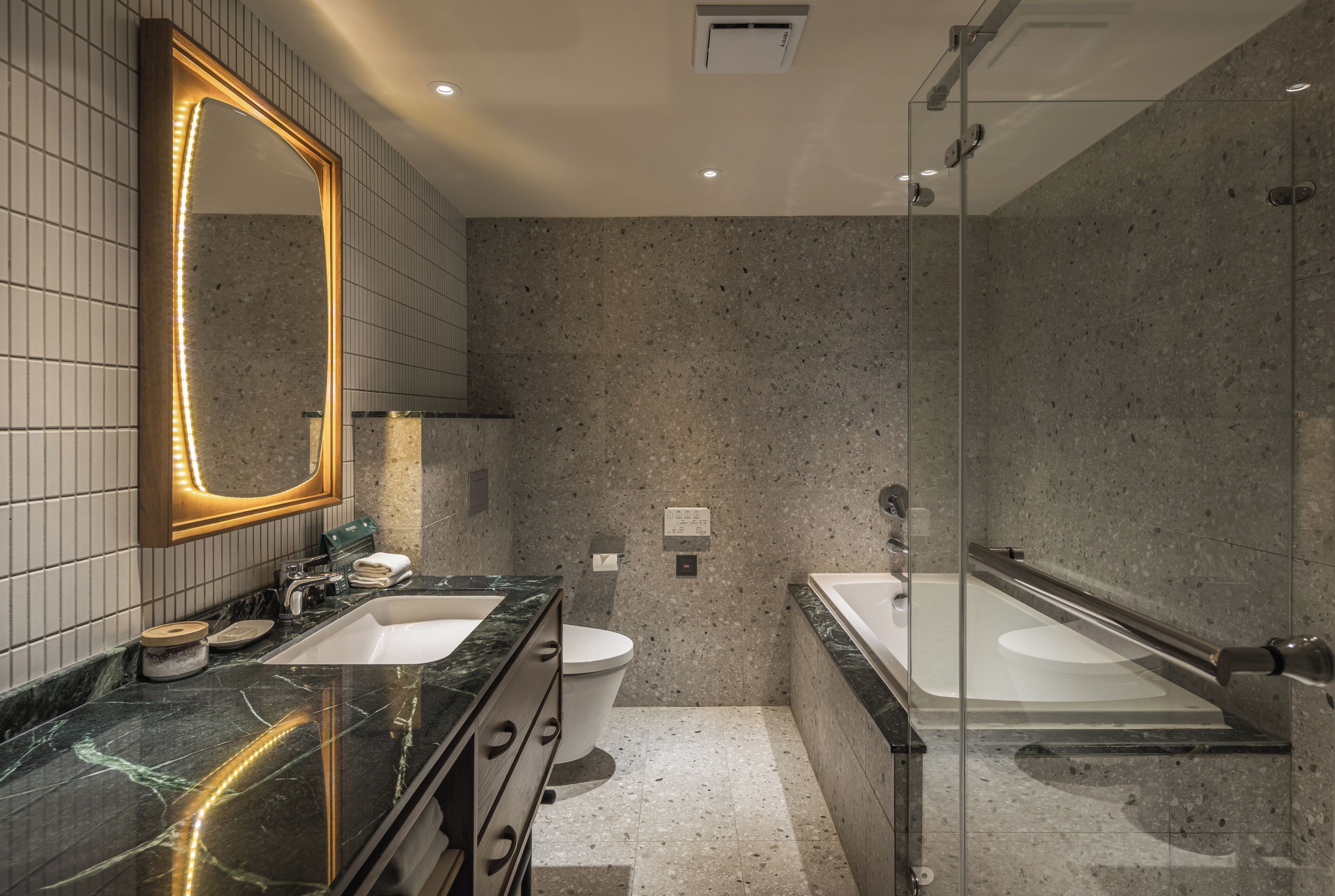 Un baño moderno con dos lavamanos, inodoro y ducha con mampara de vidrio.