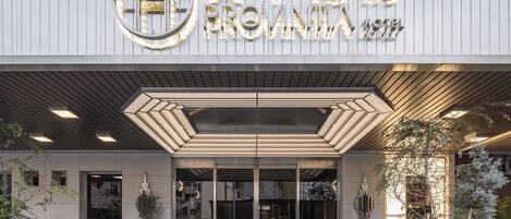 The entrance of a hotel with a modern design, featuring a prominent sign with Chinese characters and the name "PROVINIA HOTEL".