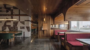 A modern restaurant interior with wooden accents, marble walls, and seating areas.