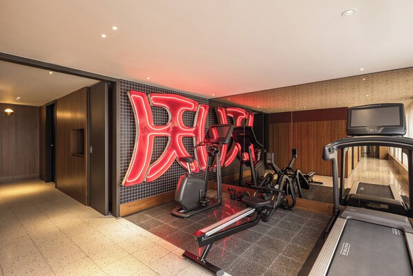 Un gimnasio moderno con equipamiento de ejercicio, una cinta de correr y un gran letrero de neón.