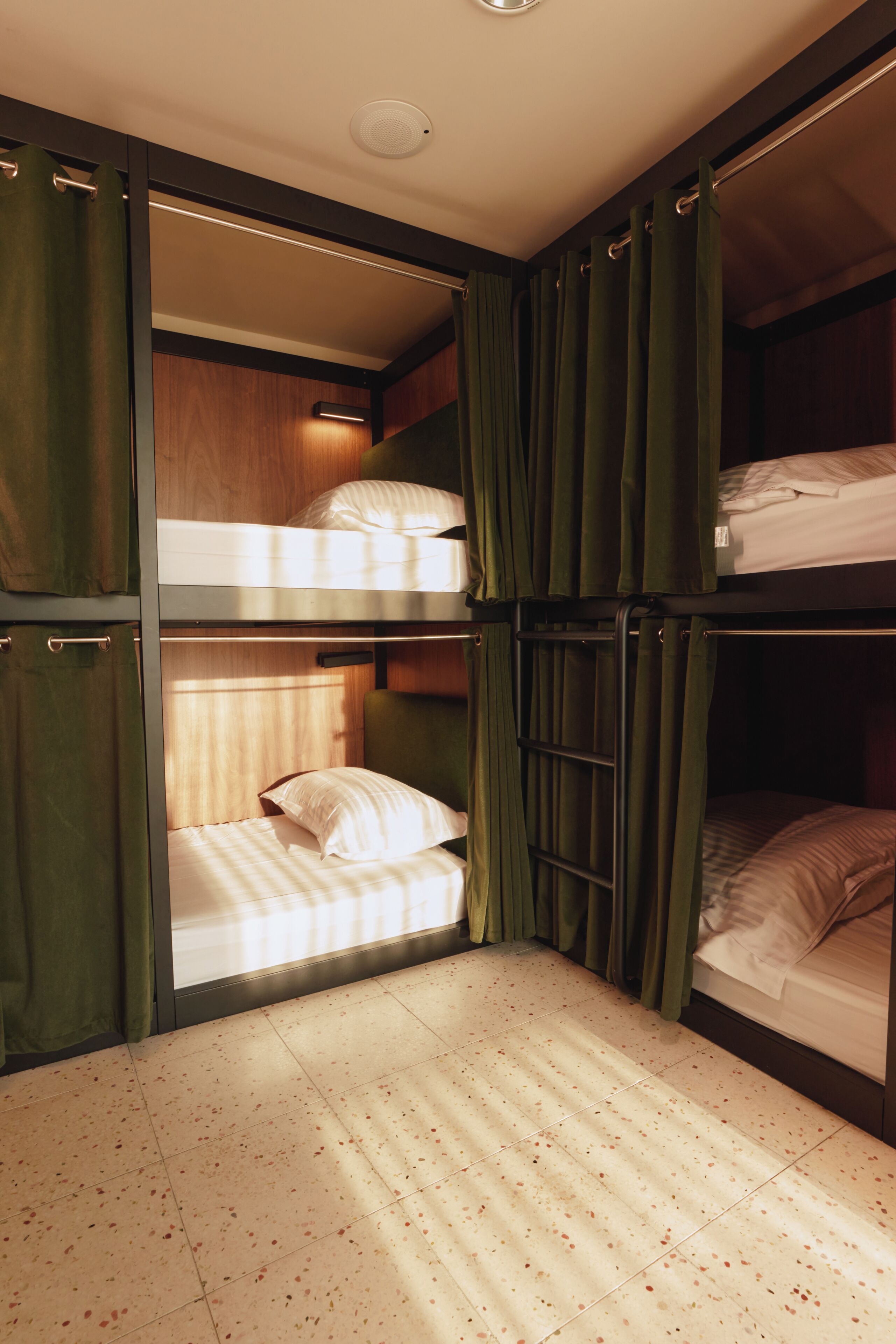 A bunk bed room with curtains, a ceiling light, and a tiled floor.