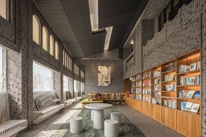 L’intérieur d’une bibliothèque moderne, avec des étagères, des espaces de lecture et une table centrale.