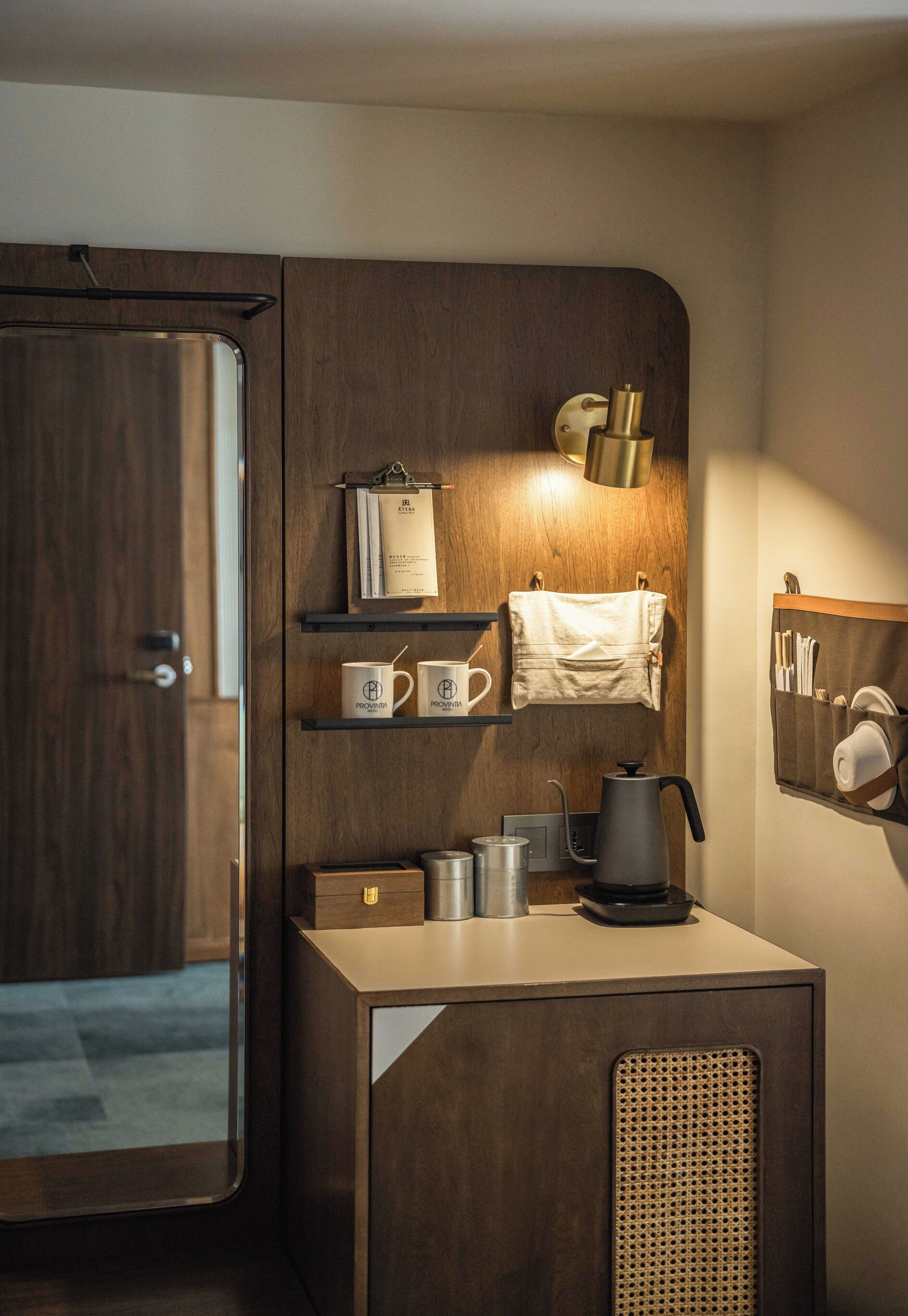 A compact kitchenette with a wooden cabinet, a coffee maker, and a kettle.