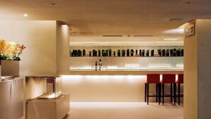 A modern bar area with a long counter, stools, and a display of bottles. - San Want Hotel Taipei (Taipei)