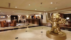 A hotel lobby with a reception desk, seating area, and a large golden statue. - San Want Hotel Taipei (Taipei)