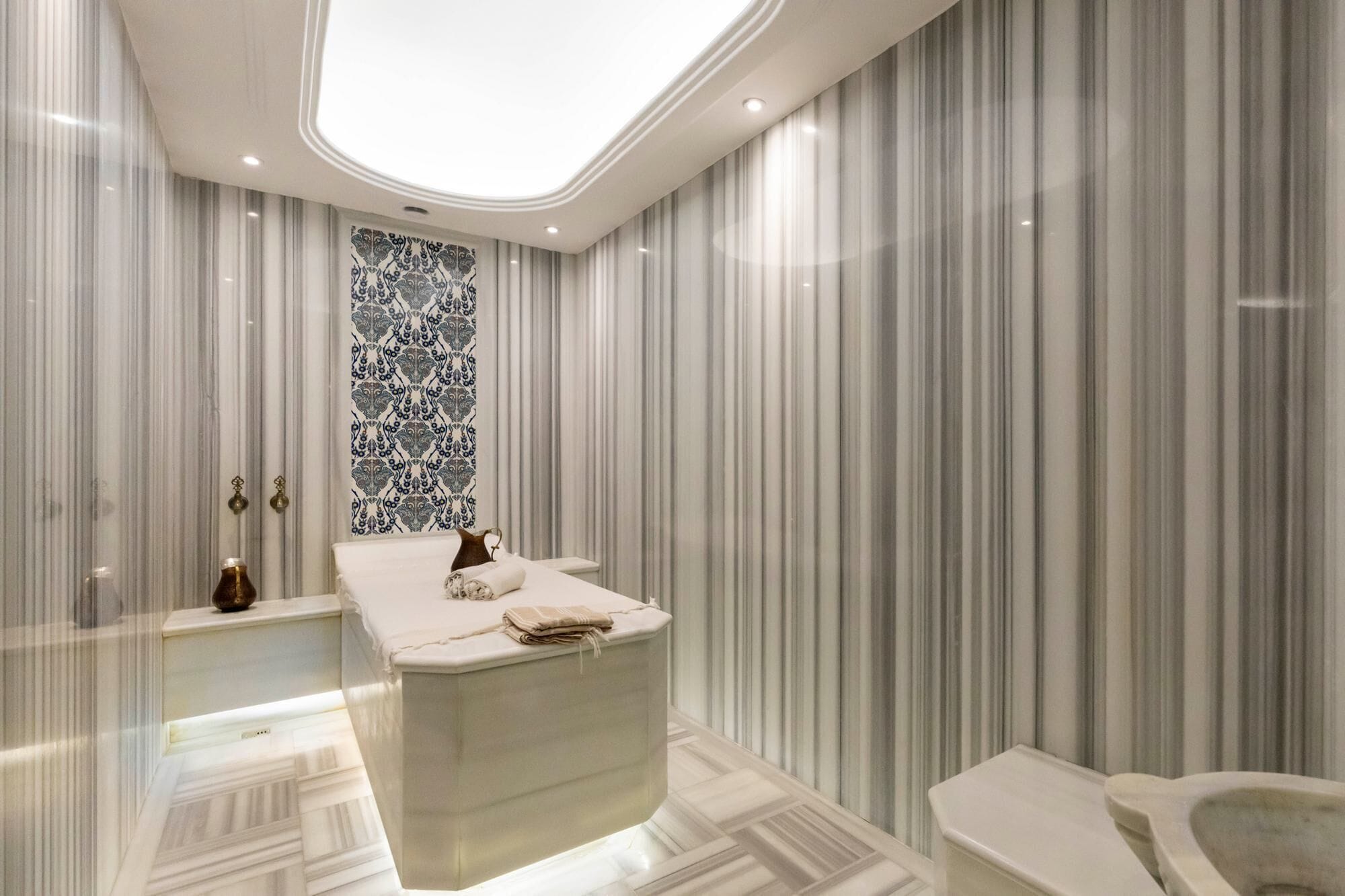 A modern bathroom with a central sink, a large mirror, and a toilet.