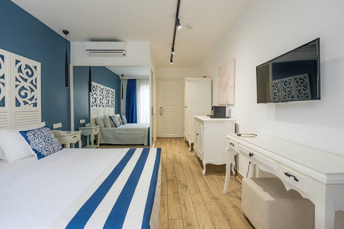 Une chambre d’hôtel avec un lit, un bureau, une télévision et une armoire.