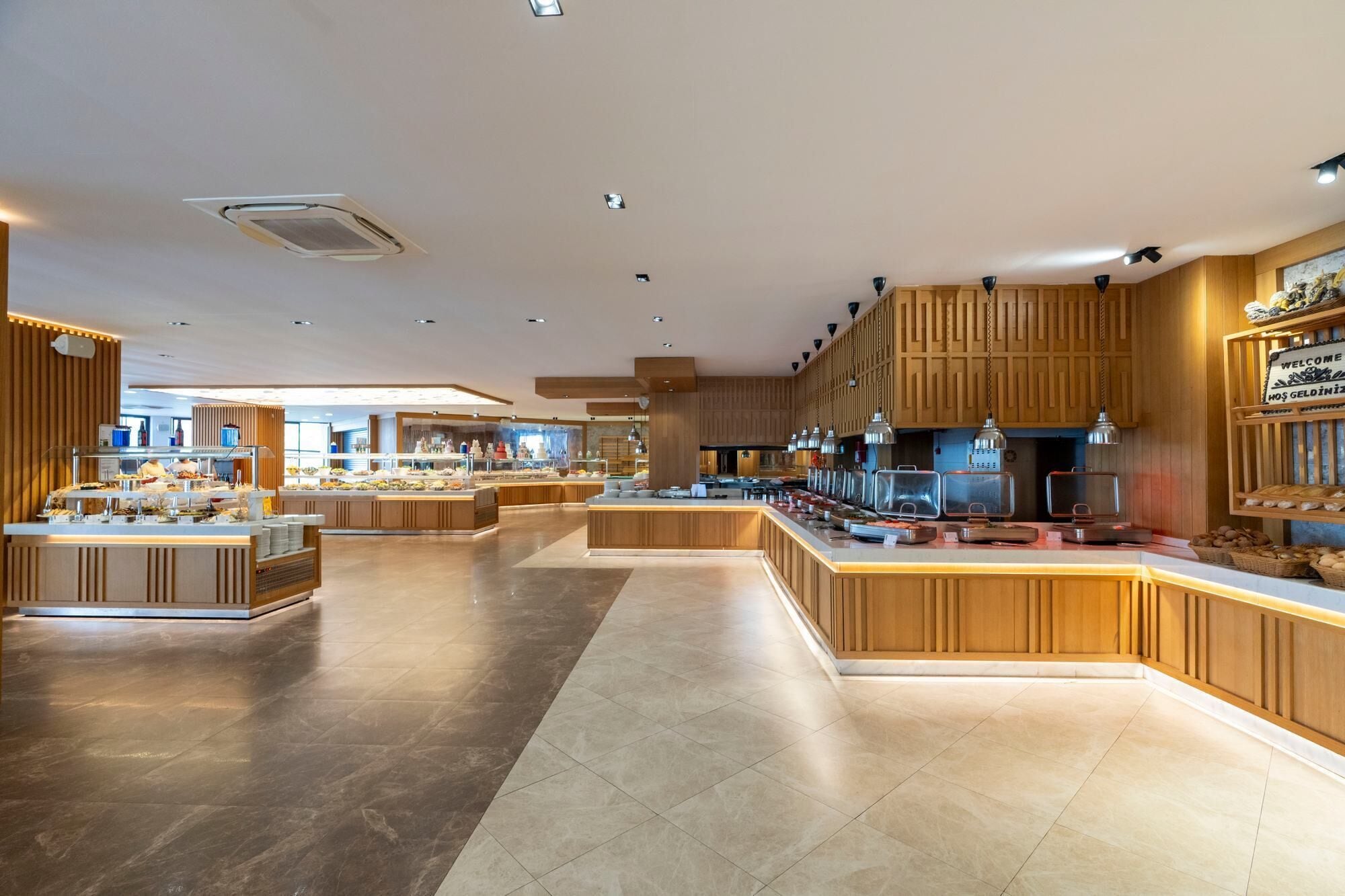 Amplia zona de buffet moderna con múltiples estaciones de servicio y una isla central.