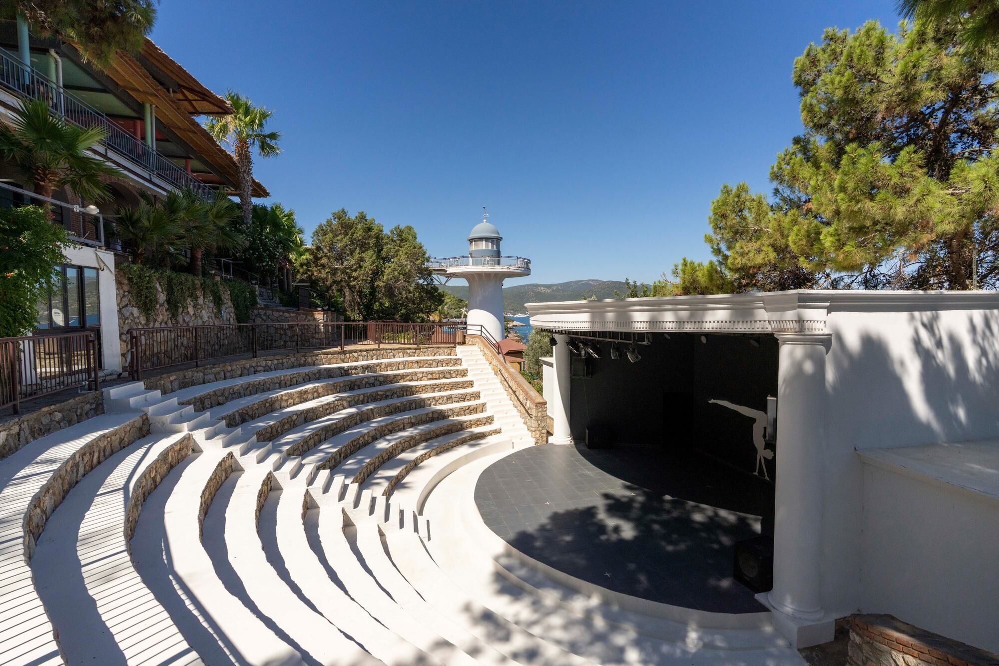 An outdoor amphitheater with stone steps and a white structure with columns.