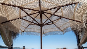 A wooden deck with a thatched umbrella, wooden lounge chairs, and mattresses. - Blue Dreams Resort-Ultra All Inclusive (Bodrum)