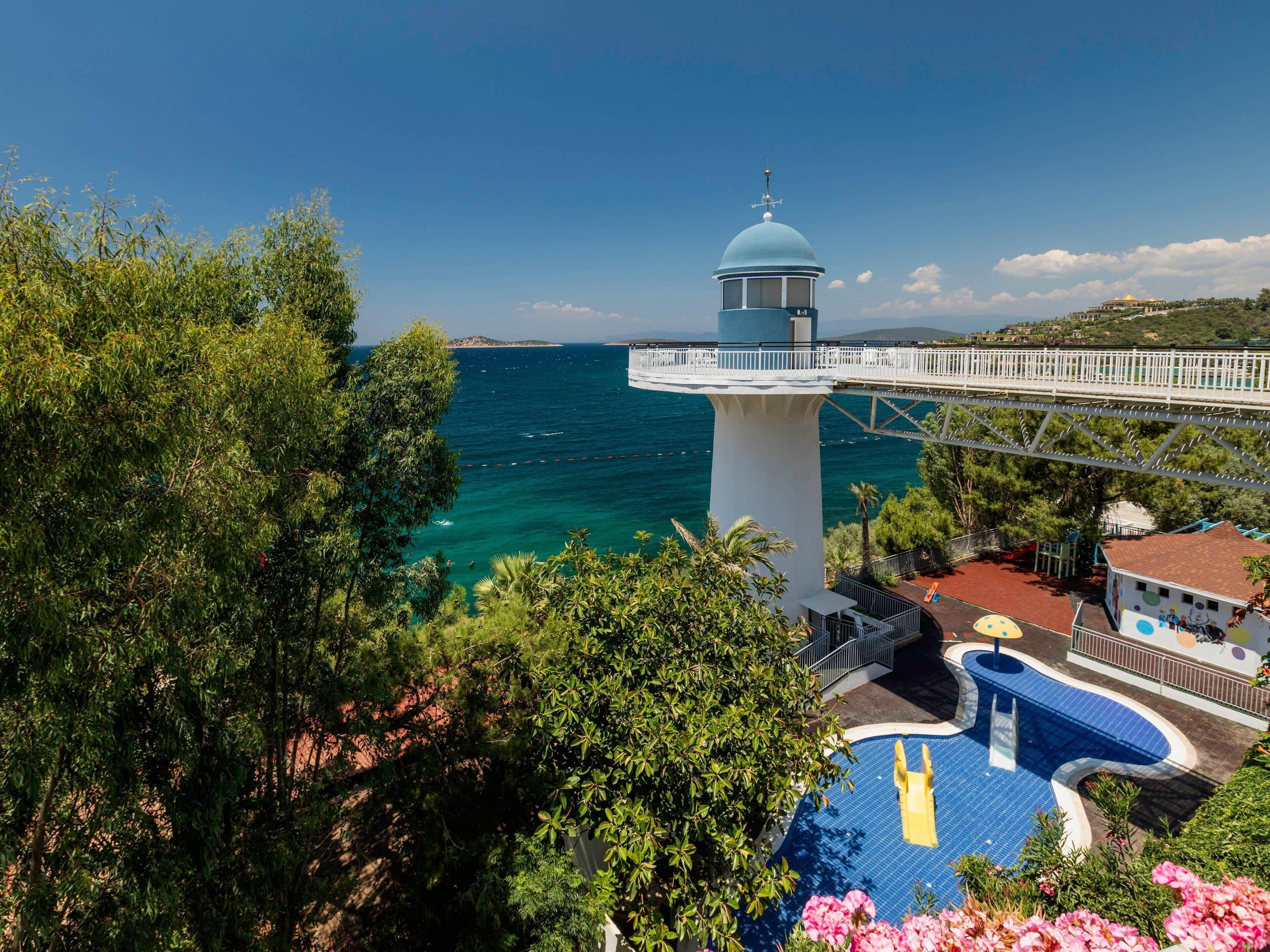 A lighthouse with a white tower and blue dome, overlooking a turquoise sea.