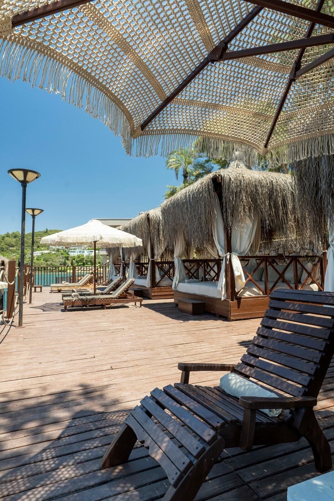A wooden deck with lounge chairs and thatched umbrellas, suggesting a resort setting.