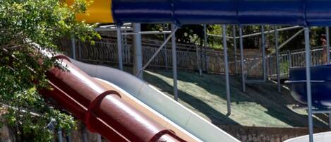 A child in a swimming pool with water slides in the background.