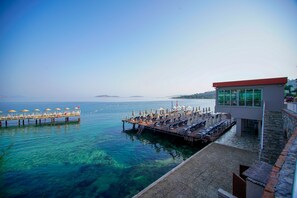 A waterfront property with a pier, outdoor seating area, and a building with large windows.