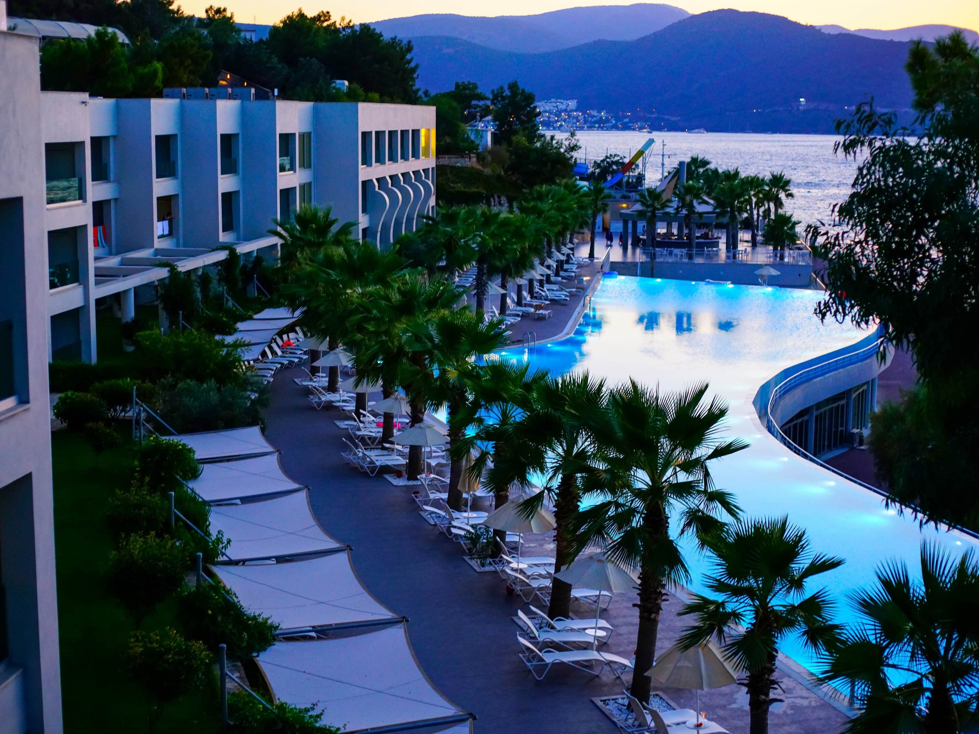 Un resort con piscina, sillas de descanso y vistas al mar.