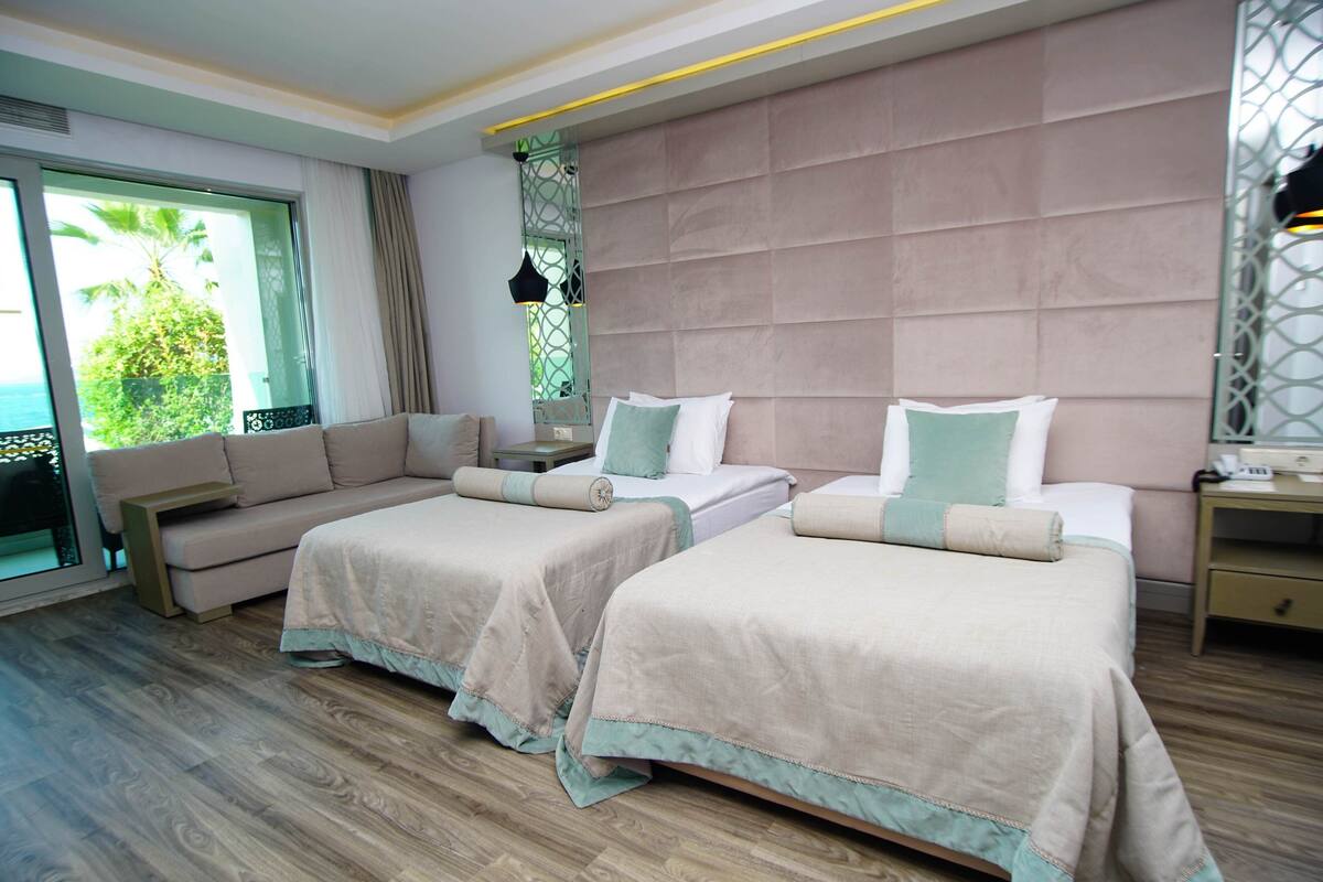 Une chambre d’hôtel avec deux lits, un canapé, une table de chevet et une vue sur l’extérieur.