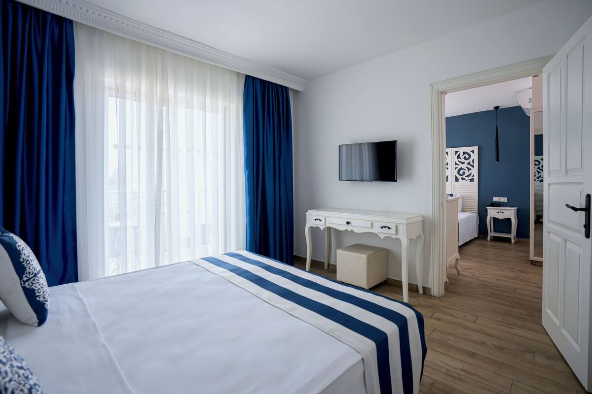 Une chambre d’hôtel avec un lit, un bureau, une télévision et une salle de bain, visibles à travers une porte ouverte.