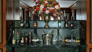 A bar area with a marble countertop, a large vase of flowers, and various bottles of alcohol. - La Chambre du Marais (Paris)