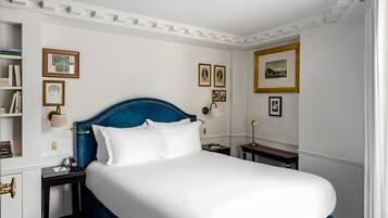 Habitación de hotel ordenada con una cama grande, mesitas de noche y cuadros en las paredes.