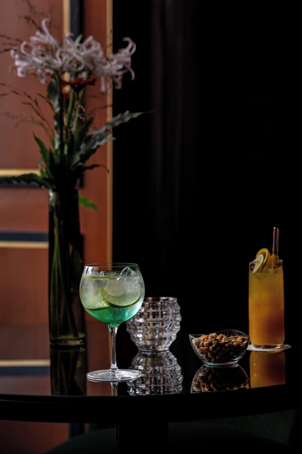 A table with three drinks, a bowl of nuts, and a vase of flowers. - La Chambre du Marais (Paris)