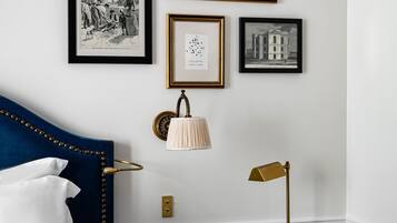 A hotel room with a bed, a desk, and a chair. There are framed pictures on the wall.