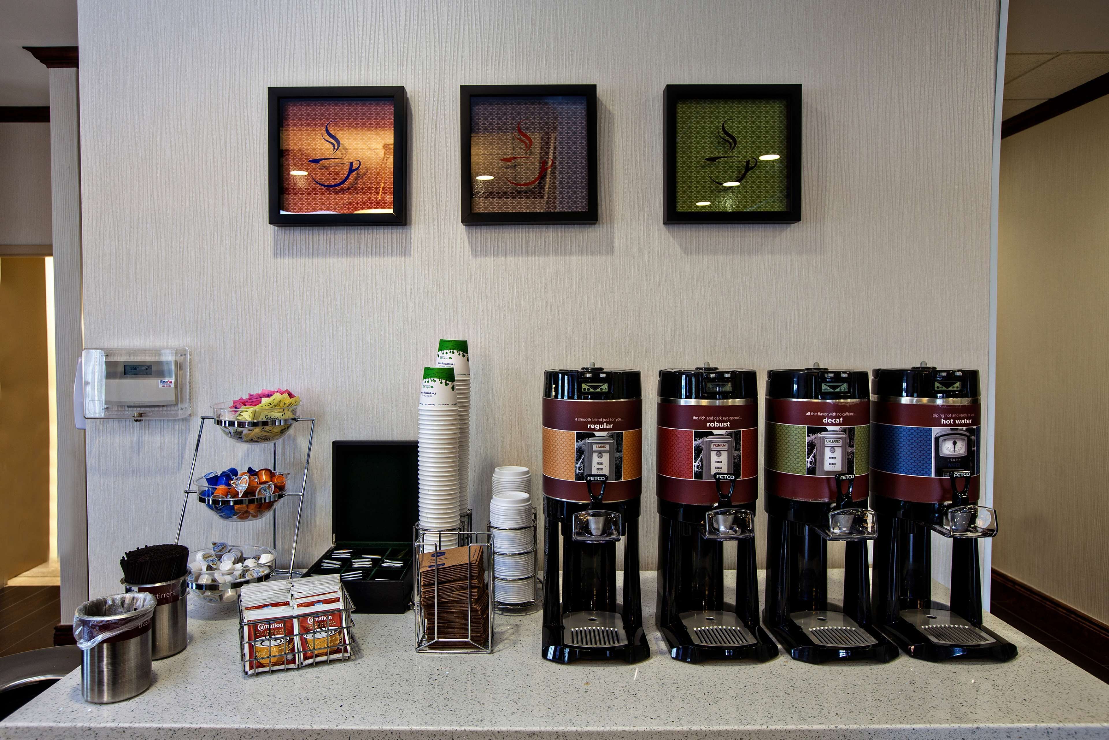 A coffee station with multiple coffee dispensers, a beverage dispenser, and a snack station with cups and bowls.