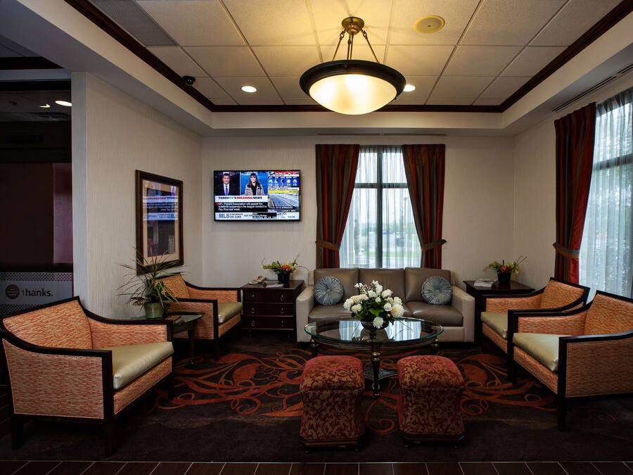 Un hall d’hôtel avec un ensemble de canapés, des fauteuils, une table basse et un écran de télévision diffusant une chaîne d’information.