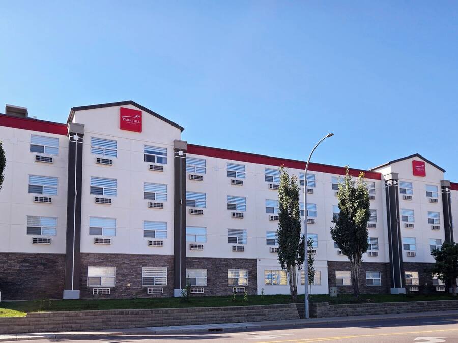 Un hotel de varios pisos con fachada roja y blanca, múltiples ventanas y techo plano.
