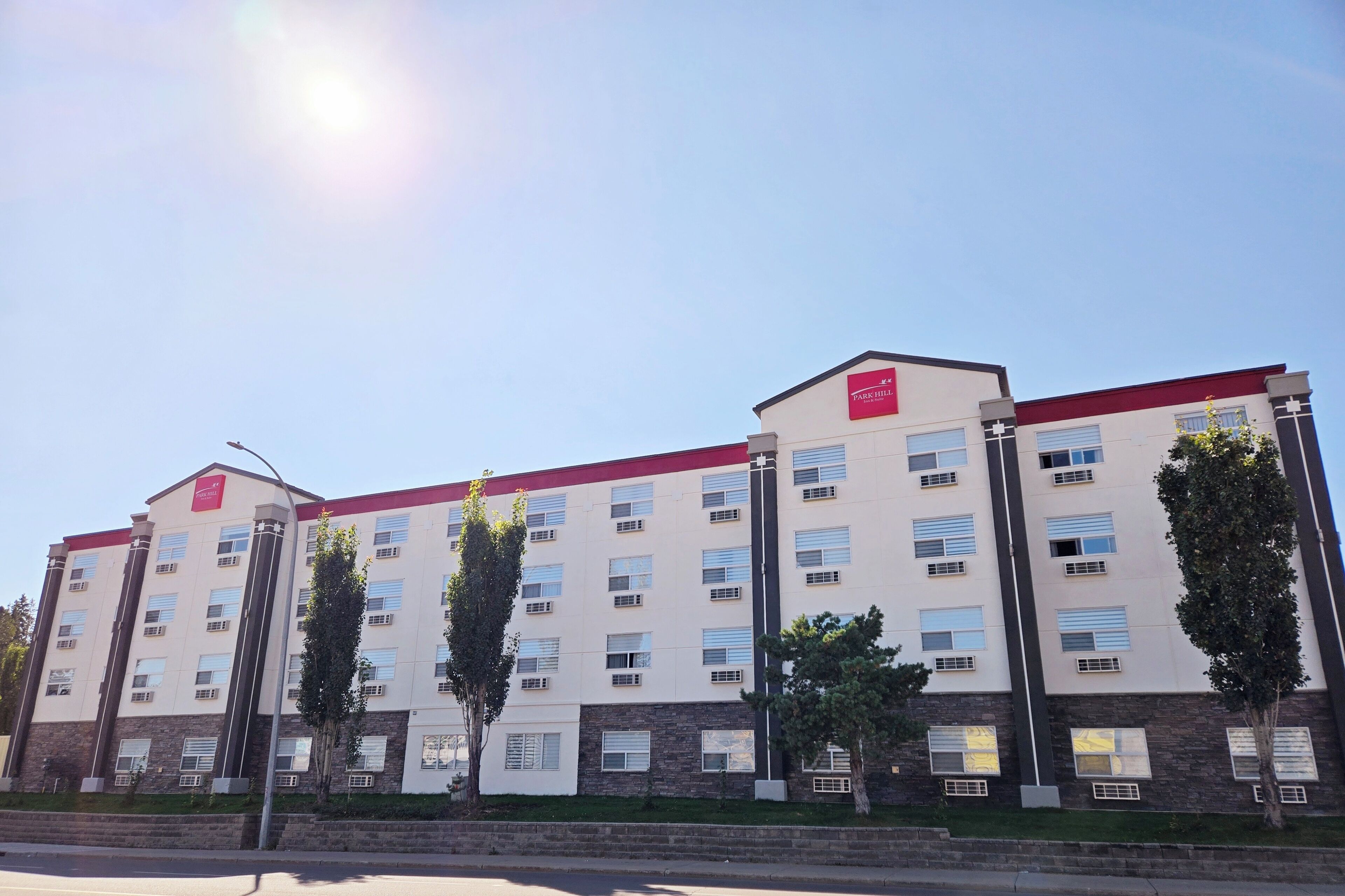 A multi-story building with a red and white facade, multiple windows, and a flat roof.