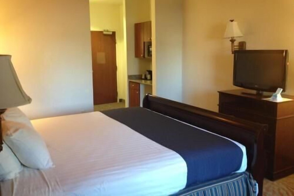 Une chambre d’hôtel avec un lit, une télévision, une lampe et une vue sur le couloir.