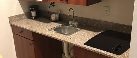 A compact kitchen with a microwave, sink, and coffee maker.
