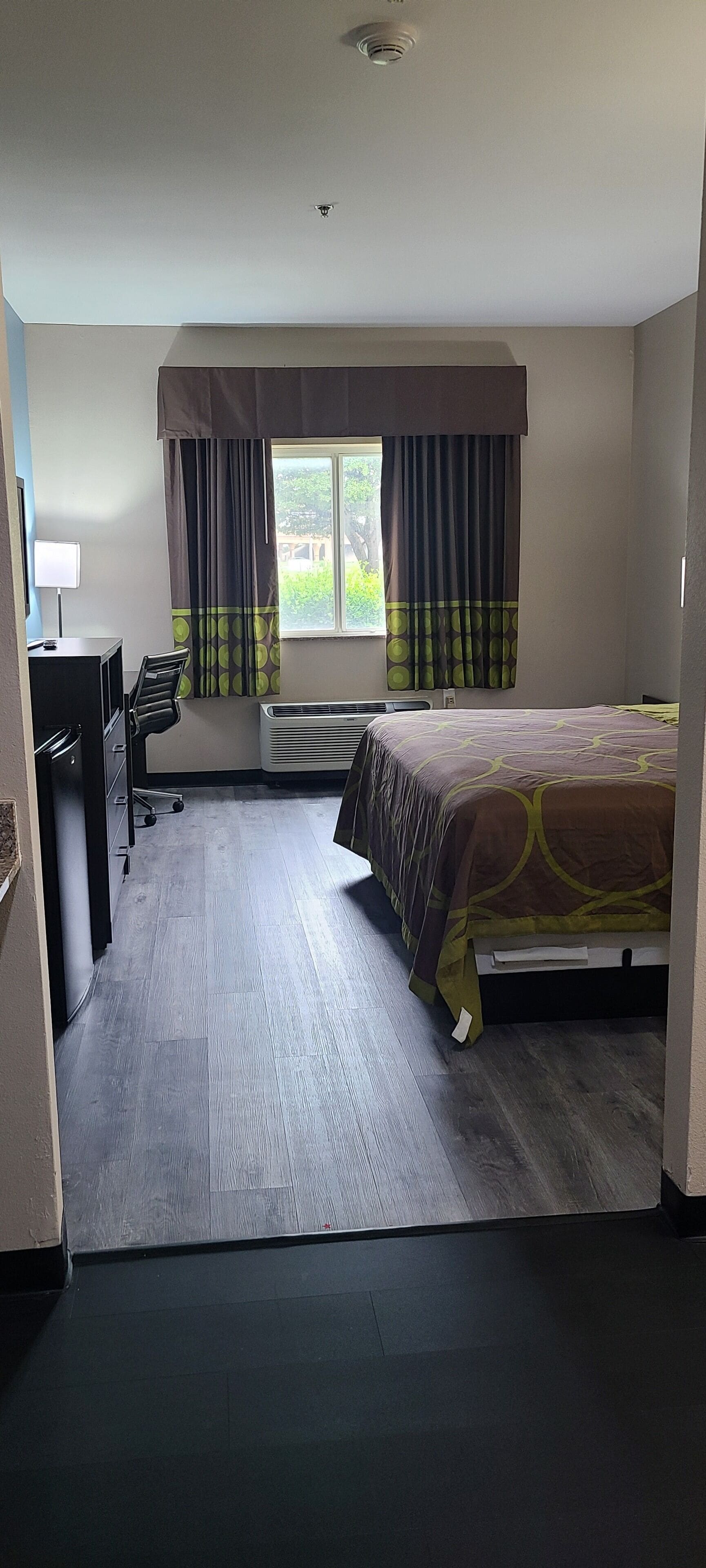 A hotel room with a bed, a desk, and a chair.