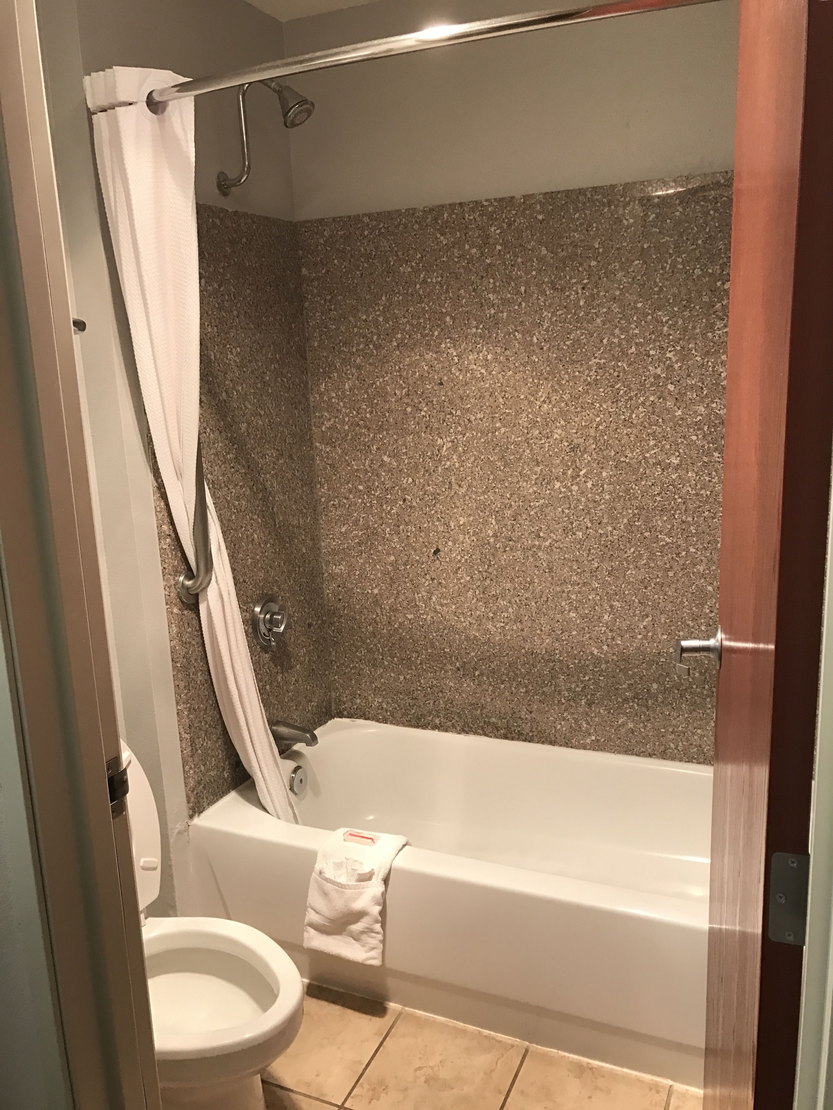 A bathroom with a bathtub, toilet, and shower curtain.