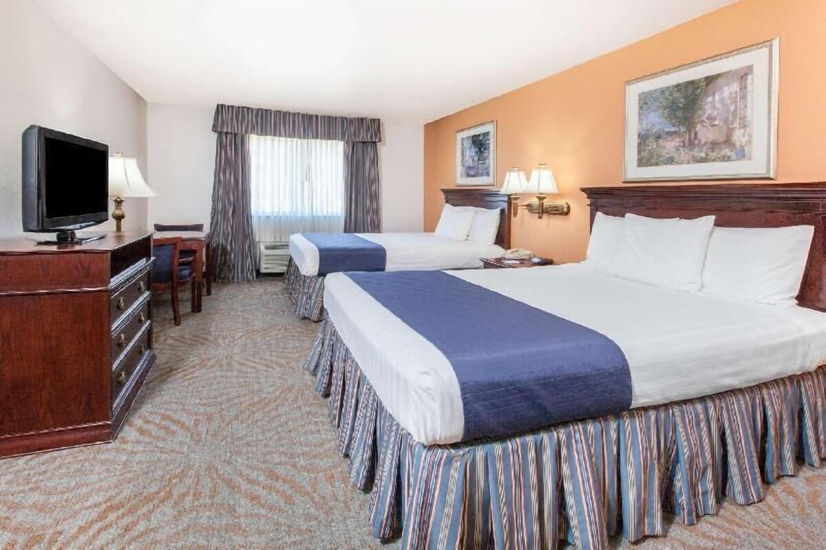 Une chambre d’hôtel avec deux lits, une télévision, un bureau et une commode.