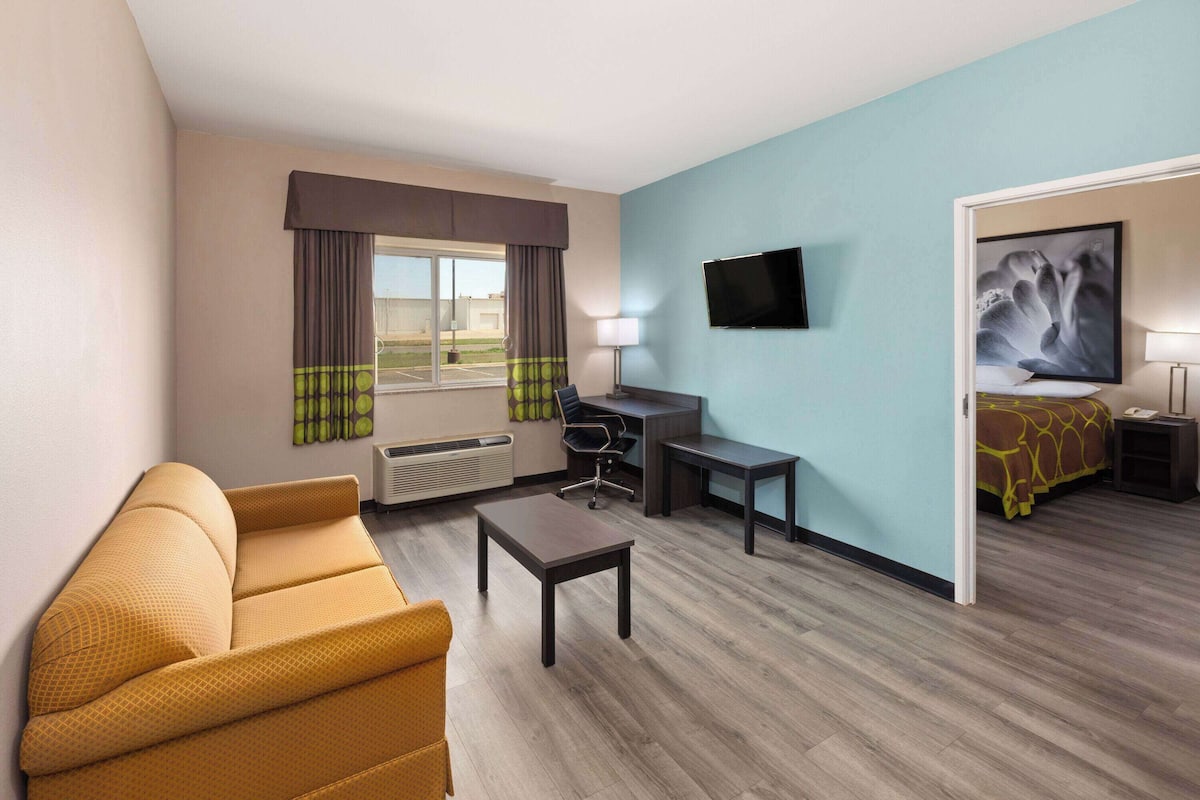 Een hotelkamer met een bank, bureau, stoel, televisie en bed.