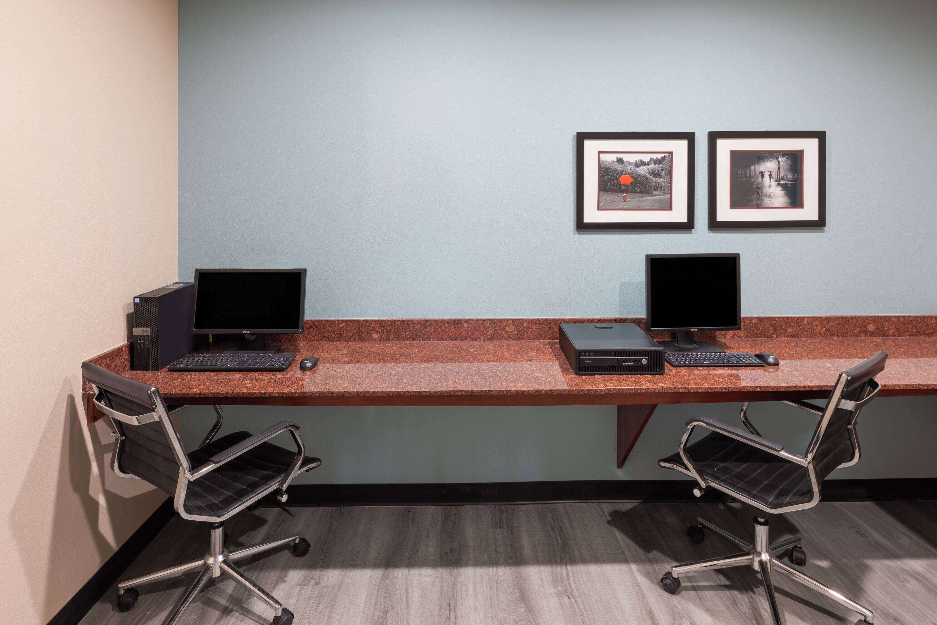 Un espace de travail comprenant deux bureaux, chacun équipé d’un ordinateur et d’un clavier, ainsi que deux chaises de bureau.