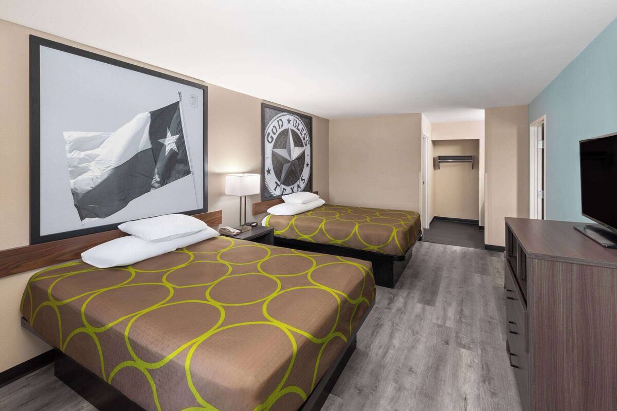 Een hotelkamer met twee bedden, een televisie, een bureau en een kledingkast.