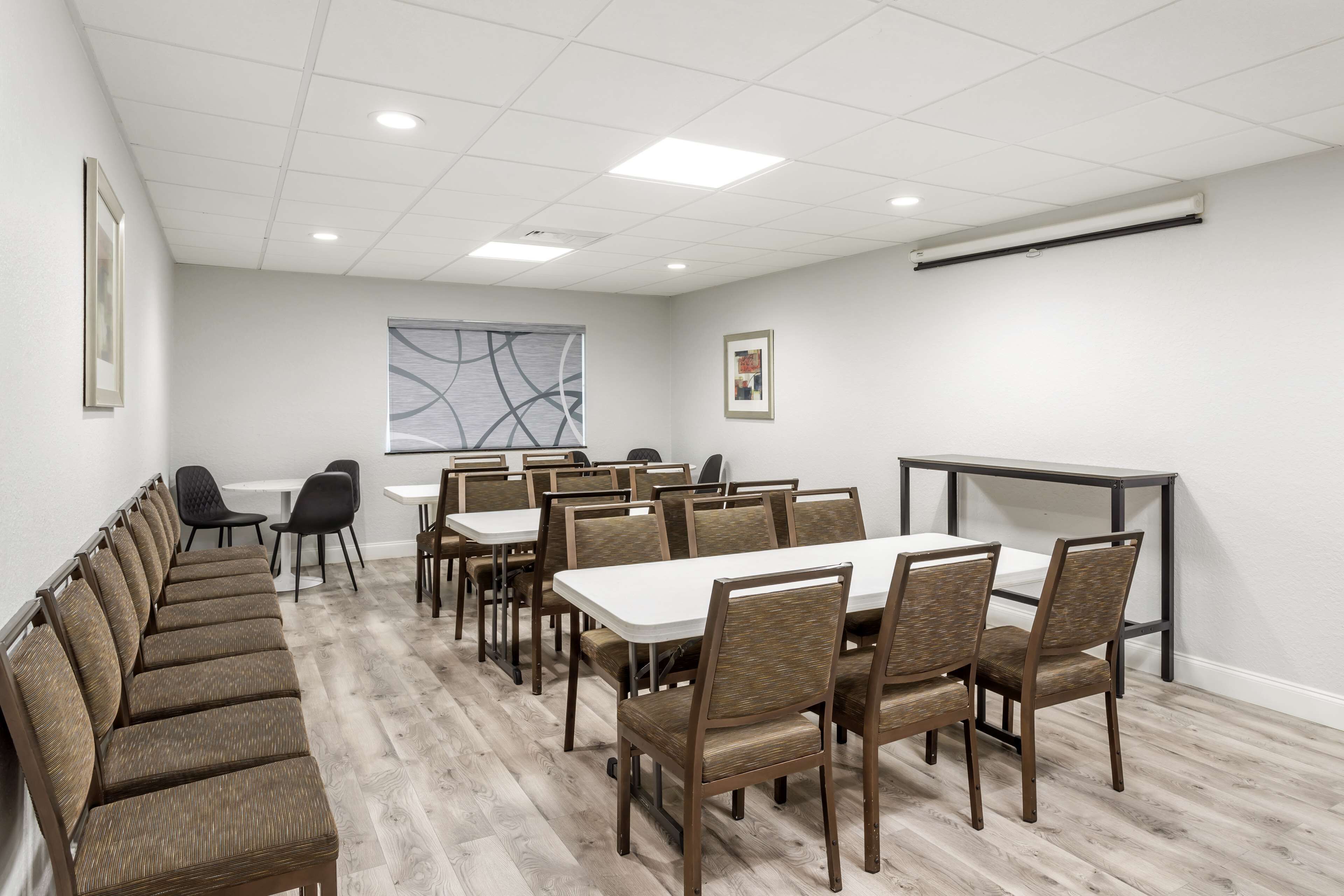 A conference room with a long table and chairs, a whiteboard, and a window with abstract art.
