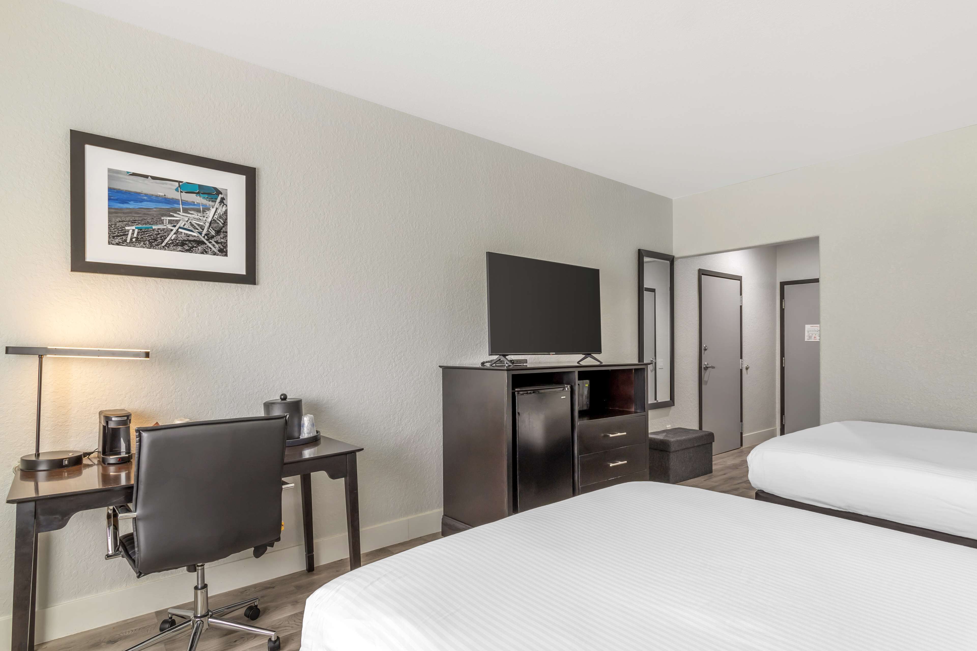 A hotel room with a bed, a desk with a chair, a television, and a wardrobe.