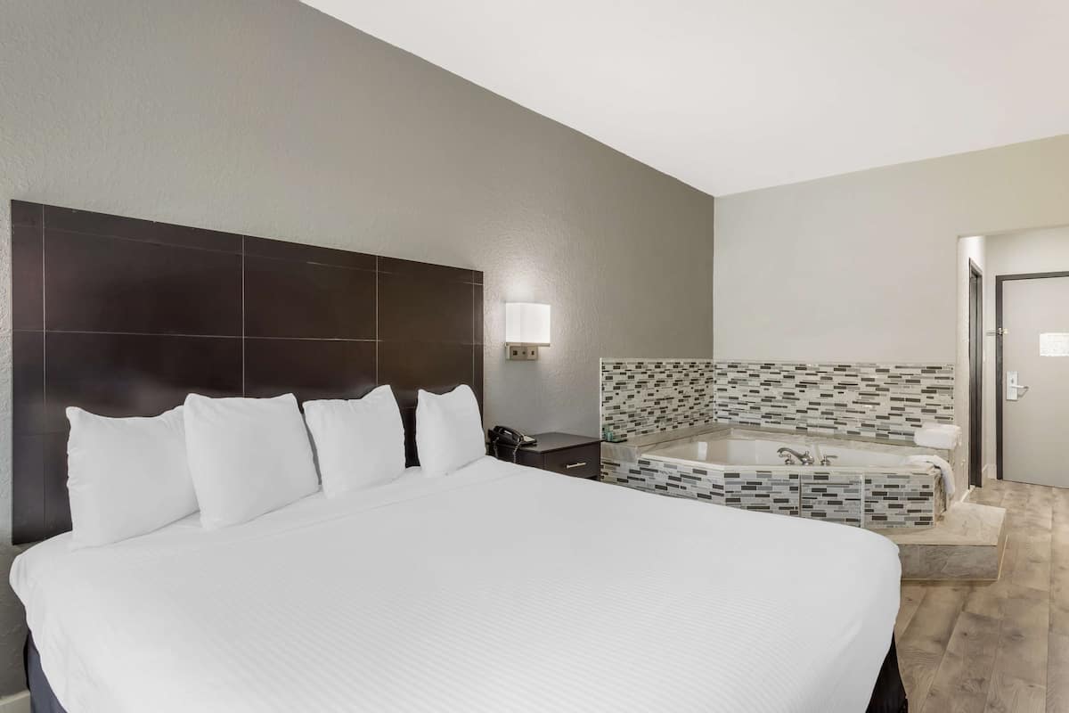 Ein Hotelzimmer mit einem großen Bett, einem Badezimmer mit einer Wand aus Mosaikfliesen und einer Tür.