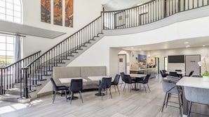 A spacious indoor area with a staircase, seating arrangements, and a kitchen area. - Best Western Texas City I-45 (Texas City)
