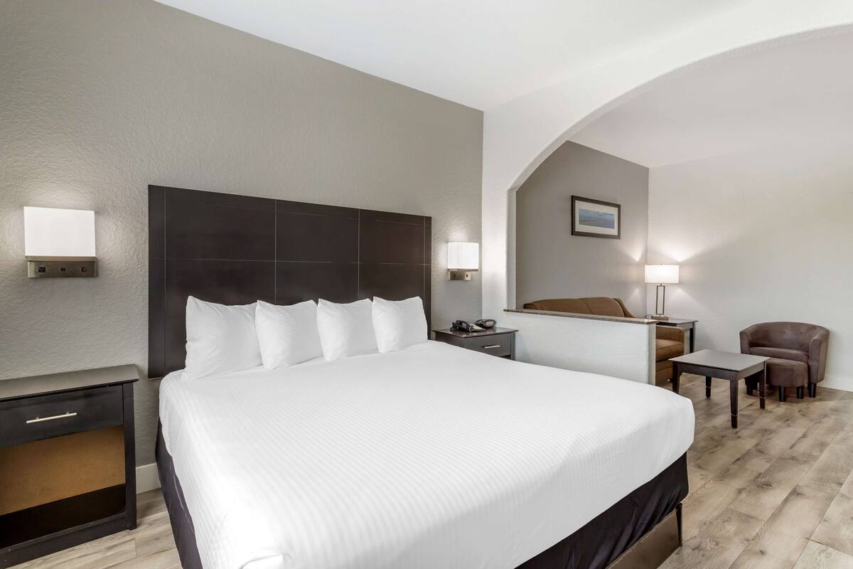 Ein Hotelzimmer mit einem großen Bett, einem Schreibtisch, einem Sessel und einem kleinen Tisch.
