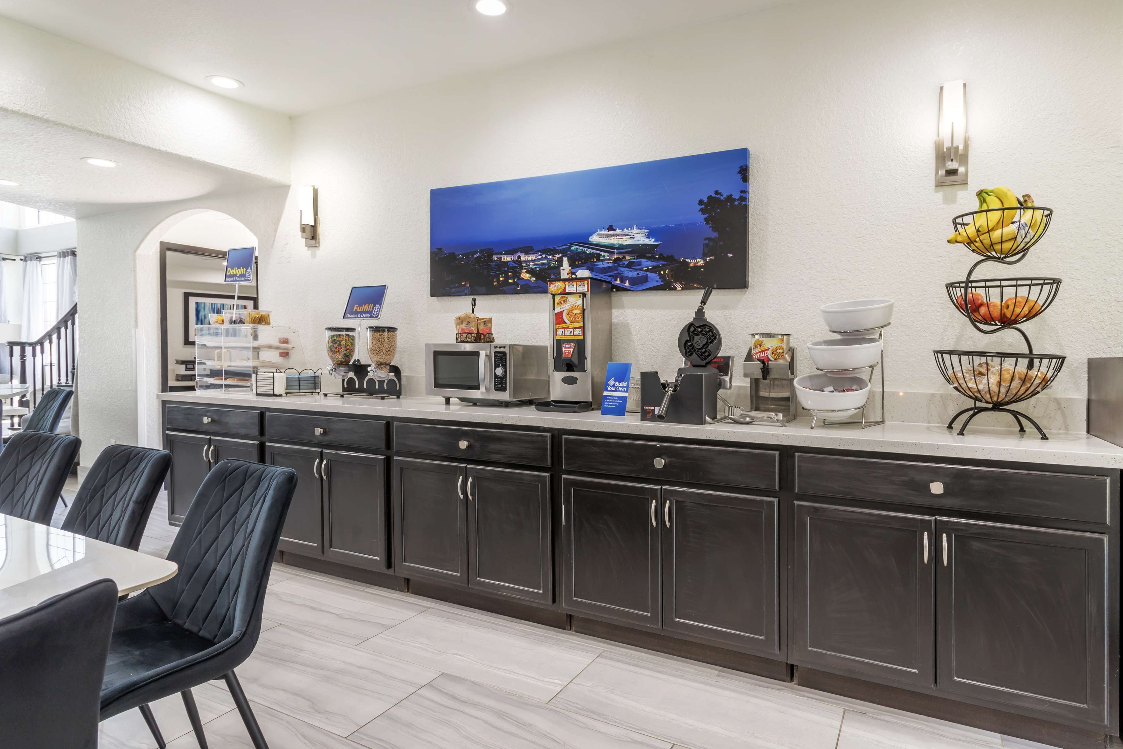 A modern kitchen with dark cabinets, a white countertop, and a dining area with a table and chairs.