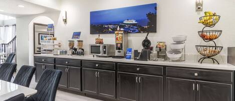 A modern kitchen with dark cabinets, a white countertop, and a dining area with a table and chairs.