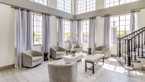 A spacious living room with high ceilings, large arched windows, and a staircase. - Best Western Texas City I-45 (Texas City)