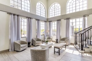 A spacious living room with high ceilings, large arched windows, and a staircase. - Best Western Texas City I-45 (Texas City)