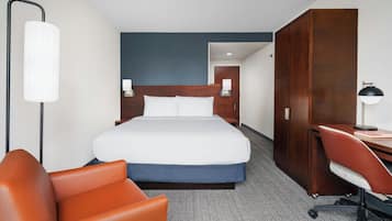 Una habitación de hotel con una cama grande, un escritorio, una silla y un armario.