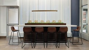 Una cocina moderna con barra, que cuenta con una encimera larga, taburetes de bar y una lámpara colgante.