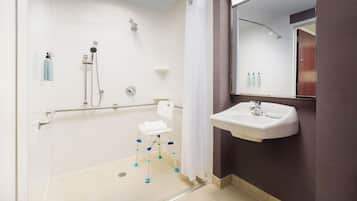 A bathroom with a shower, a toilet, a sink, and a mirror.