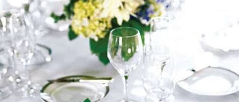 A table set with clear glassware and white plates, accompanied by a bouquet of flowers.